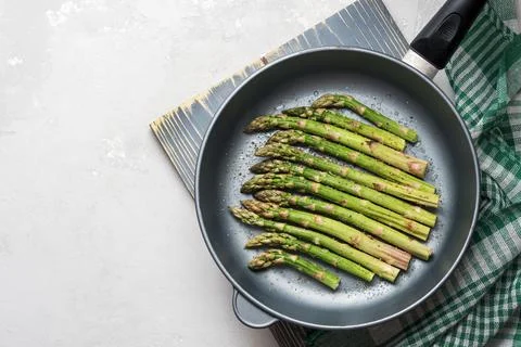 The process of making asparagus in a frying pan. Fresh asparagus in a frying  Stock Photos