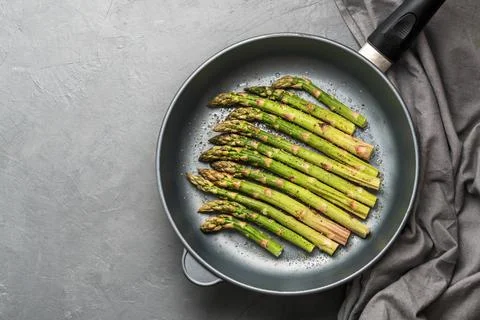 The process of making asparagus in a frying pan. Fresh asparagus in a frying  Stock Photos