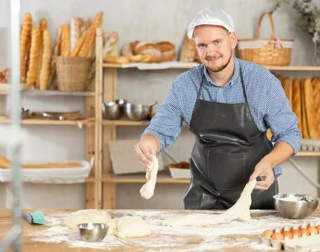 Process of making baguette, loaf or bread in bakery - baker kneads and rolls the Stock Photos