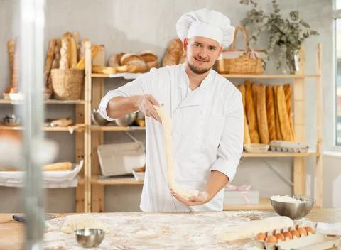 Process of making baguette, loaf or bread in bakery - baker kneads and rolls the Stock Photos
