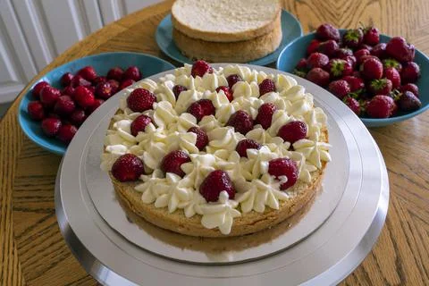 The process of making a biscuit cake is decorated with cream and strawberries Stock Photos