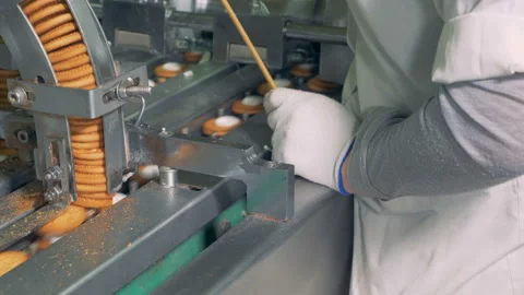 Process of making biscuits by a factory machine. Worker controlls the production 库存影片 85925575