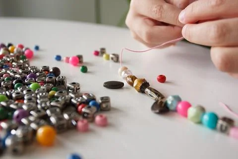 Process of making a bracelet from a thread and colored beads, concept of hobb Stock Photos