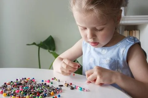 Process of making a bracelet from a thread and colored beads, concept of hobb Stock Photos