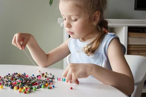 Process of making a bracelet from a thread and colored beads, concept of hobb Stock Photos