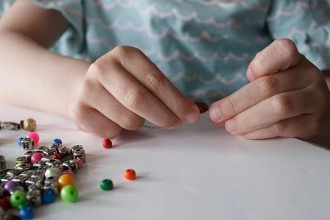 Process of making a bracelet from a thread and colored beads, concept of hobb Foto stock