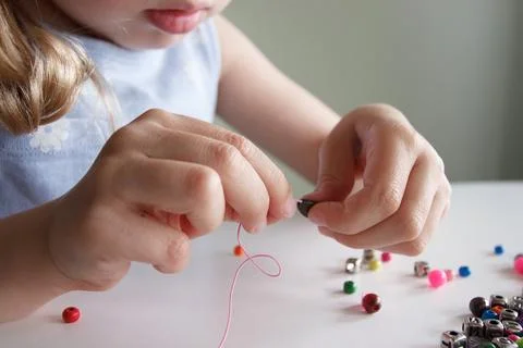 Process of making a bracelet from a thread and colored beads, concept of hobb 스톡 사진