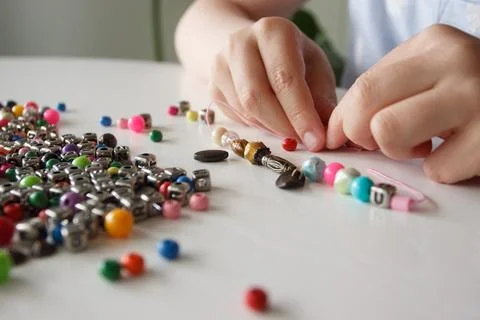 Process of making a bracelet from a thread and colored beads, concept of hobb Stock Photos