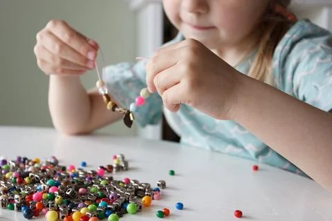 Process of making a bracelet from a thread and colored beads, concept of hobb Foto stock