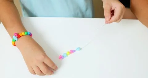 Process of making a bracelet from a thread and colored beads 库存照片