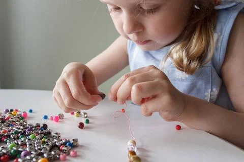 Process of making a bracelet from a thread and colored beads, concept of hobb Stock Photos