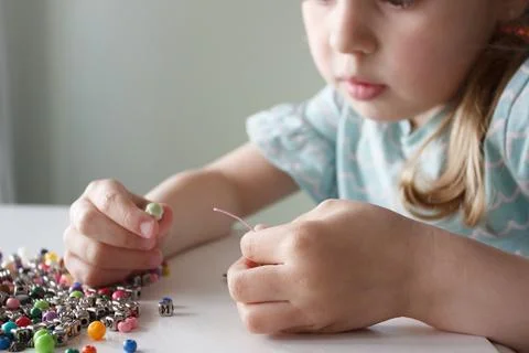 Process of making a bracelet from a thread and colored beads, concept of hobb Stock Photos
