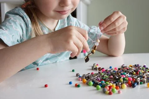 Process of making a bracelet from a thread and colored beads, concept of hobb 库存照片