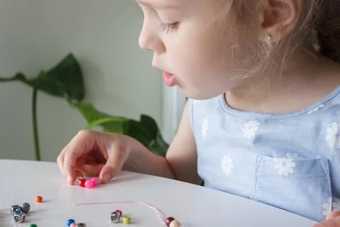 Process of making a bracelet from a thread and colored beads, concept of hobb Stock Photos