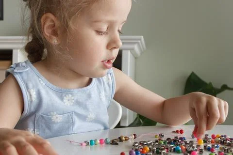 Process of making a bracelet from a thread and colored beads, concept of hobb Stock Photos