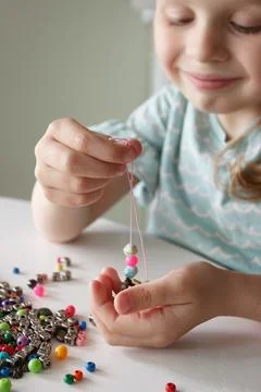 Process of making a bracelet from a thread and colored beads, concept of hobb 库存照片
