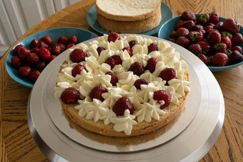 The process of making a cake. Decorating the biscuit with cream and strawberr Foto stock