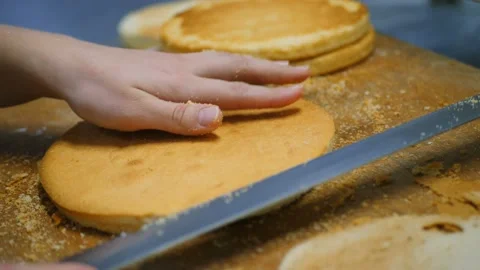 The process of making a cake.Confectioners slices biscuit Stock Footage 121705786