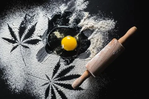 The process of making cannabis pastries. raw broken egg, a rolling pin, flour Foto stock