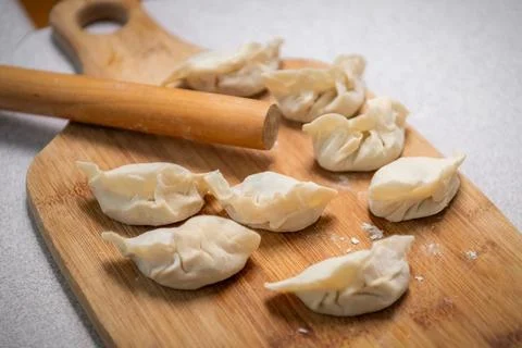 Process of making chinese dumplings. Raw dough and rolling pin on wooden ch.. Stock Photos