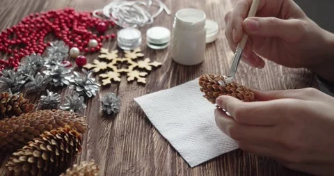 Process of making Christmas decoration at home. Human hands painting a fir cone Stock Footage 195224274