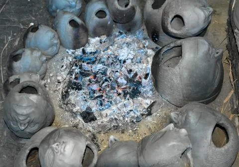 Process of making clay idol by drying the clay heads in front of fire. Stock Photos