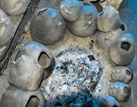 Process of making clay idol by drying the clay heads in front of fire. Stock Photos