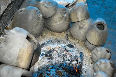 Process of making clay idol by drying the clay heads in front of fire. Stock Photos
