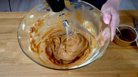 The process of making cream for chocolate cake. the chef whips the cream with a Stock Footage 157293522