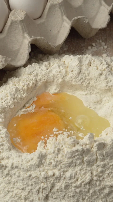 Process of Making dough. Man adding egg into pile of flour in the kitchen Stock Footage 343253858