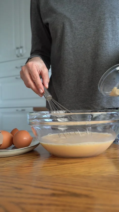 The process of making the dough.. A woman beats eggs in a bowl and adds yeast. Stock Footage 312387516