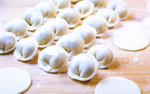 The process of making dumplings. Dumplings - Russian on a wooden background. Stock Photos