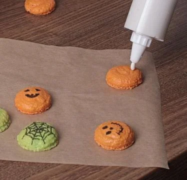 Process of making Halloween macarons. Anonymous squeezing protein cream from a Stock Photos