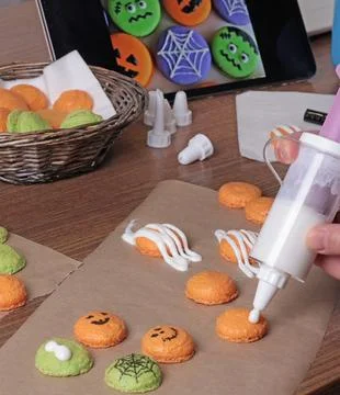 Process of making Halloween macarons. Anonymous squeezing protein cream from a Foto stock
