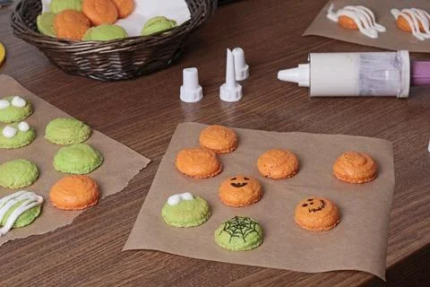 Process of making Halloween macarons. White icing in pastry syringe and cookie Stock Photos
