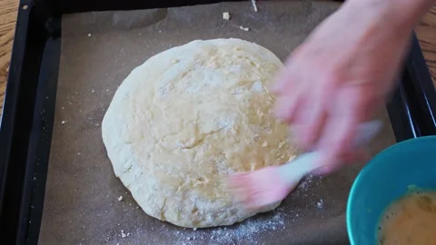 The process making homemade bread. Baker brush with egg yolk before baking with Stock Footage 202274392