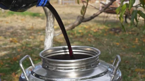 The process of making homemade grape wine. Red juice pours from a plastic Stock Footage 230133907