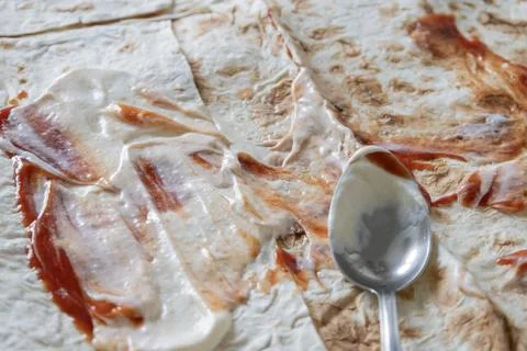 Process of making homemade shawarma: spreading white creamy sauce and red k.. Stock Photos