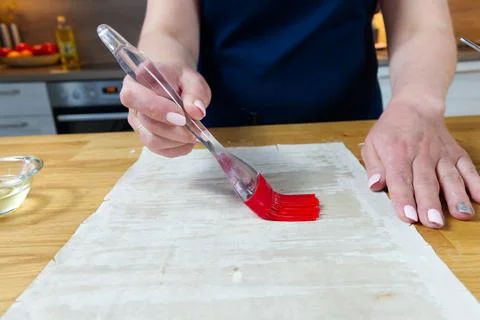 The process of making homemade snacks. The cook greases the dough with a brush Stock Photos