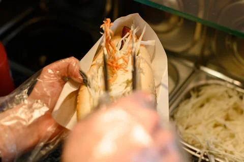 The process of making a hot dog, a worker fulfills a customer's order and p.. 库存照片