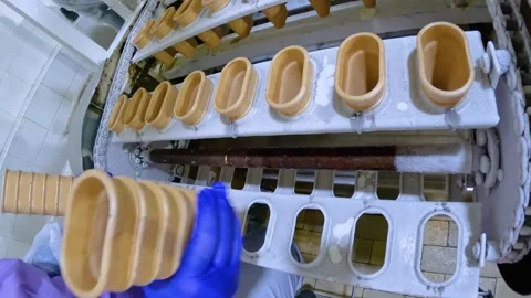 The process of making ice cream at the factory. A woman puts waffle cups on a Stock Footage 249731810