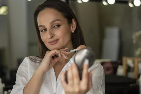 Process of making makeup. The girl is doing her own make-up. Reflection in the Foto stock