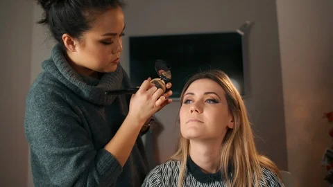 Process of making makeup. Make-up artist working with brush on model face Stock Footage 119387830