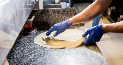The process of making pizza. Hands of chef baker making pizza at cafe kitchen Stock Photos