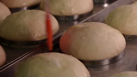 Process of making round bread. Baker applying yolks on raw dough with pastry Stock Footage 152930012