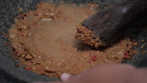 The process of making rujak seasoning using a mortar containing peanuts, kl.. Stock Footage 241374928