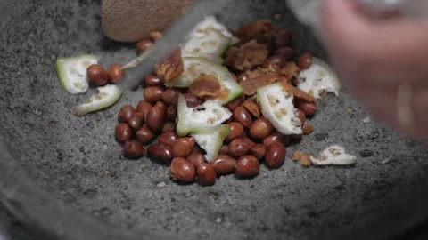 The process of making rujak seasoning using a mortar containing peanuts, kl.. Stock Footage 241375108