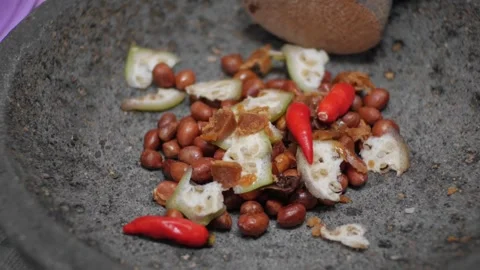 The process of making rujak seasoning using a mortar containing peanuts, kl.. Vídeos de archivo 241375145