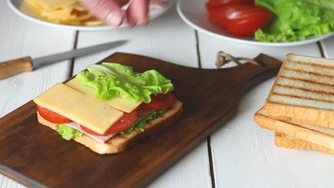 The process of making a sandwich with salad, tomato, ham and cheese. Stock Footage 147848322