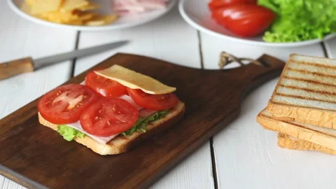 The process of making a sandwich with salad, tomato, ham and cheese. Stock Footage 147848330